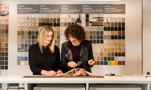 Two interior designers working together in a design library, selecting finishes